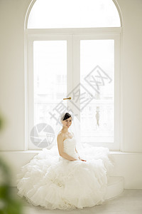 穿着婚纱坐在窗边的新娘图片