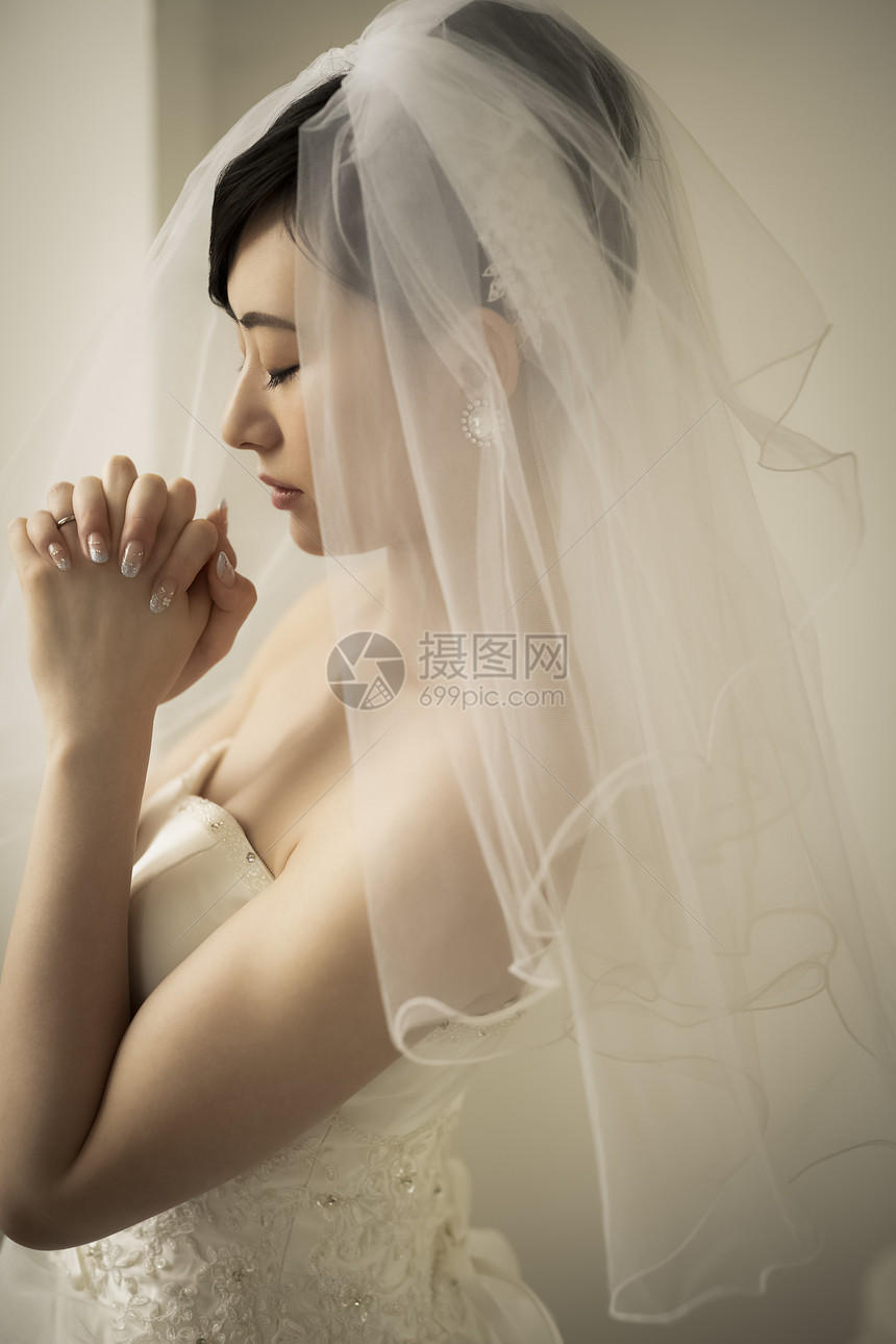 戴着头纱双手紧握祈祷的新娘图片