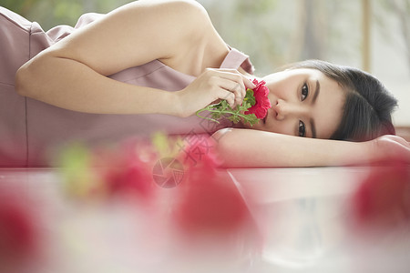 躺着拿着花的年轻女子礼服高清图片素材