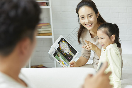 幸福家庭在客厅阅读书籍画册高清图片素材