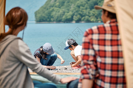 好朋友小姑娘一家四口在野外湖边露营扎帐篷背景