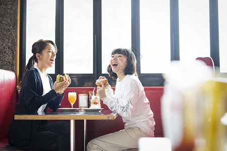 餐厅里吃汉堡聊天的闺蜜好友休假高清图片素材