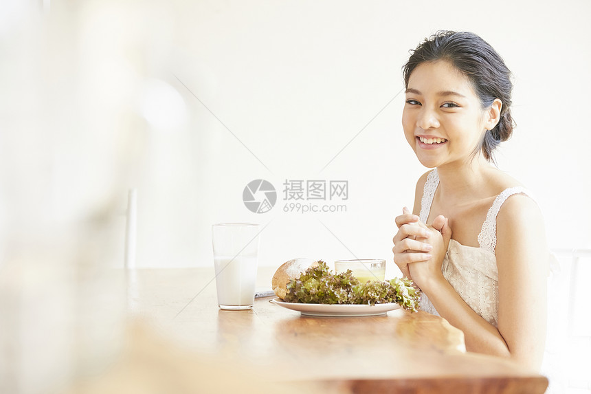 餐桌吃早餐微笑的年轻女子图片