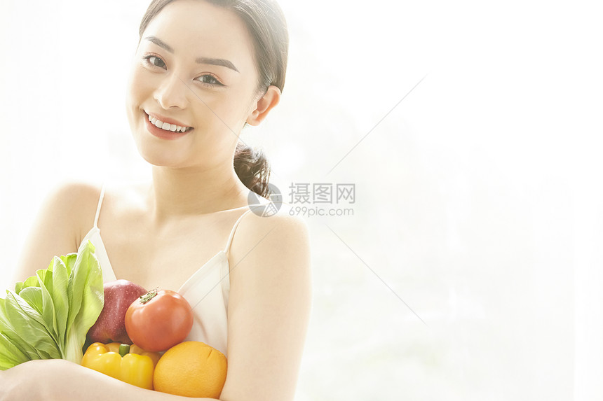 抱着蔬菜微笑的女青年图片