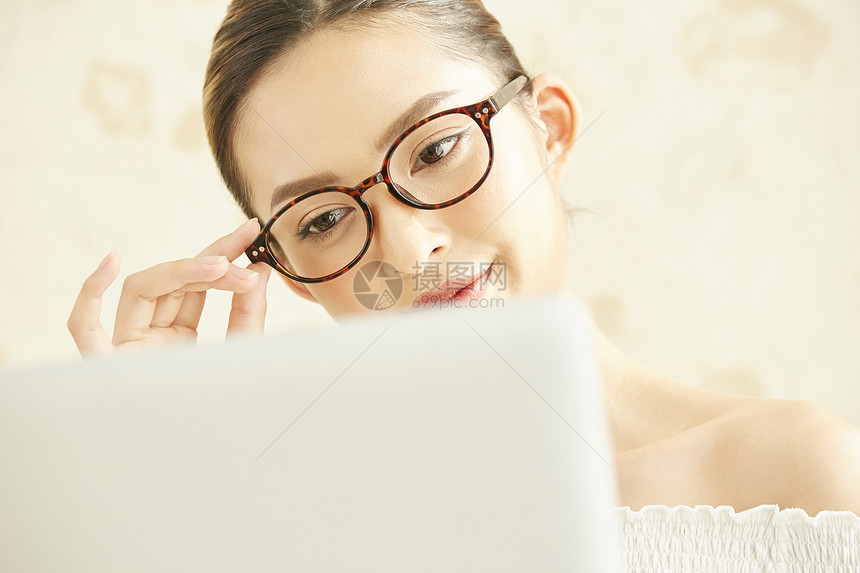 戴眼镜看着笔记本电脑的年轻女子图片