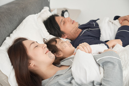 3人睡熟伙伴父母和孩子睡在床上图片