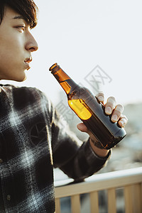 阳台边喝啤酒的男性图片