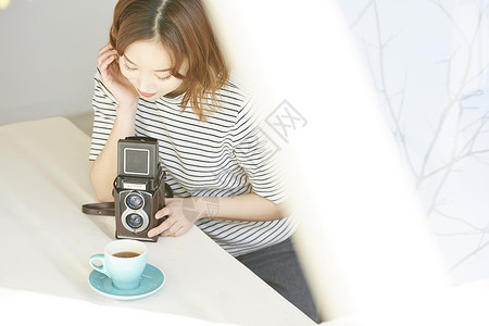 拿着相机拍咖啡的年轻女子图片