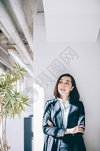 亚洲人二十多岁四十来岁倾斜在柱子的微笑的妇女在办公室图片