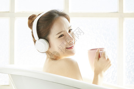 戴着耳机沐浴喝咖啡的年轻女子图片