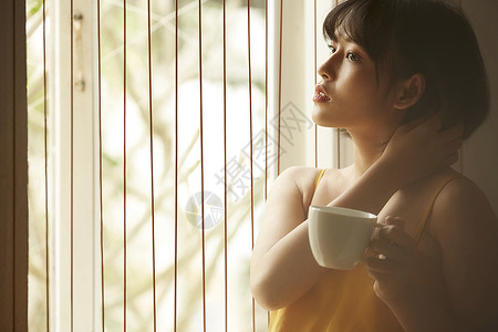 窗边拿着咖啡的女青年思考高清图片素材