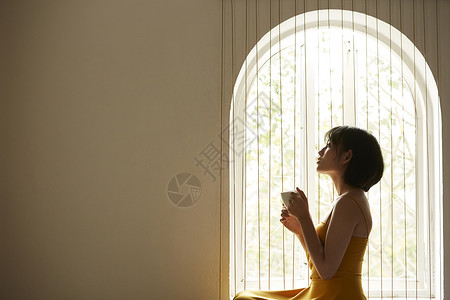 窗边享受下午茶喝咖啡的女青年礼服高清图片素材