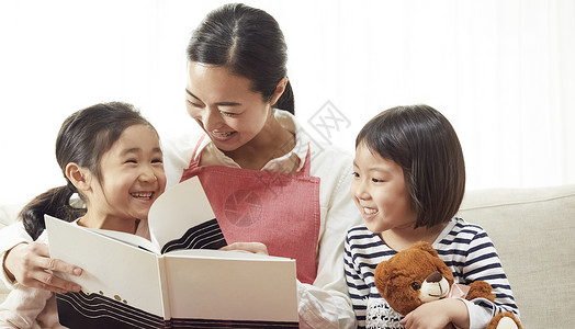 家政工作者父母和小孩笑容有老师的孩子在沙发上看书和听图片