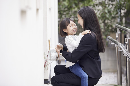 在房子外拥抱女儿的母亲图片