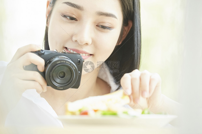 拿相机拍食物的居家女孩图片