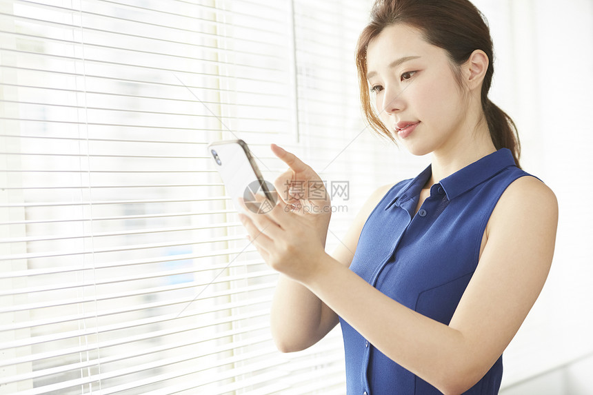 办公室窗边的职业女性看手机图片