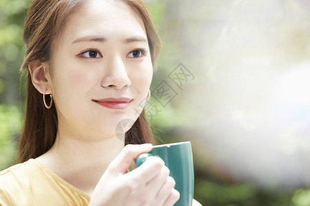 手拿咖啡喝下午茶的青年女子放松的高清图片素材