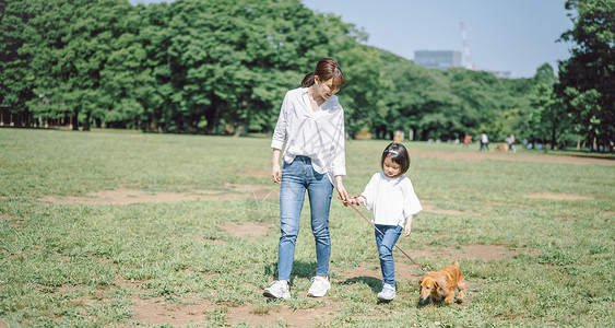 公园散步遛狗的妈妈和女儿图片