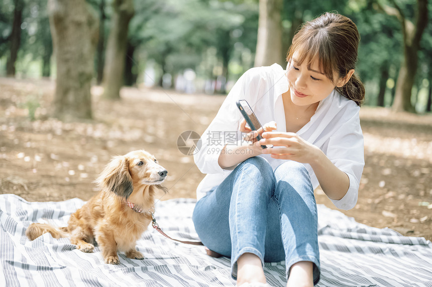 年轻女子拿着手机拍宠物狗图片