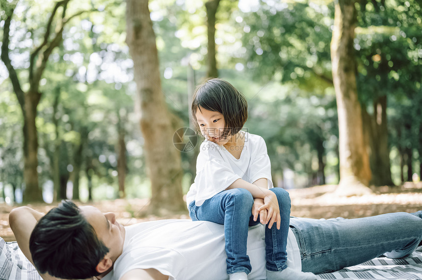 公园野餐坐在父亲身上的小女孩图片