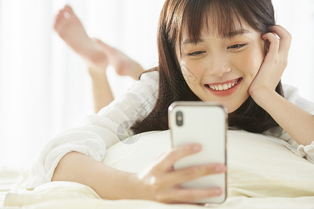 可爱女生开心的在床上看手机年轻高清图片素材