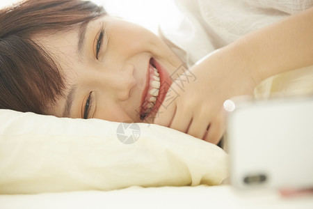 可爱女生开心的在床上看手机女性高清图片素材