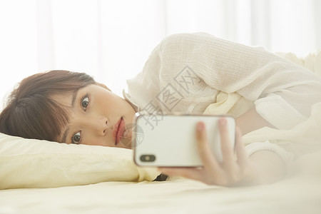 可爱女生在床上看手机年轻女子高清图片素材