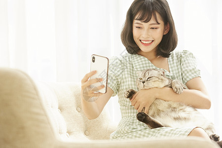 年轻女孩抱着宠物猫猫拍照图片
