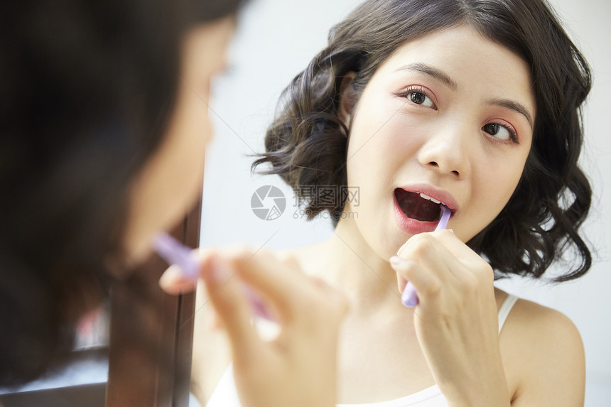对着镜子刷牙的年轻女子图片