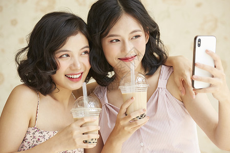 亲密姐妹开心的喝奶茶礼服高清图片素材