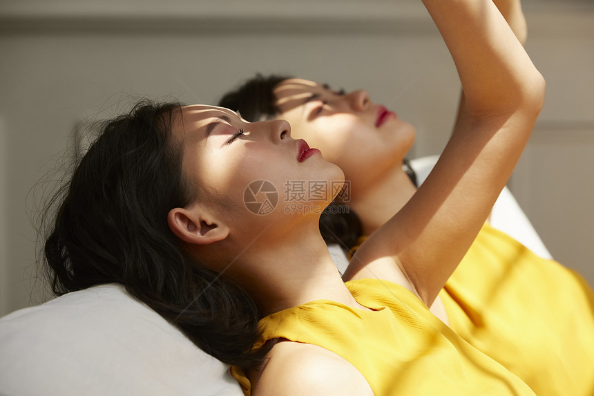 两个年轻女人躺在光影下图片
