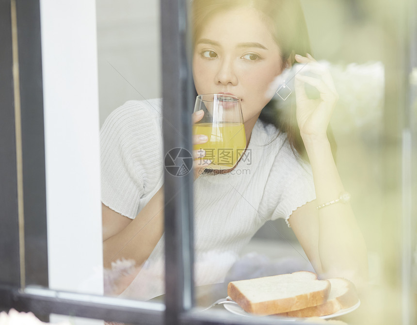 喝果汁看向窗外的年轻女子图片