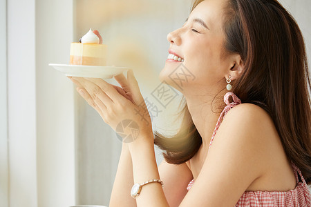 拿着甜食小蛋糕开心的年轻女子图片