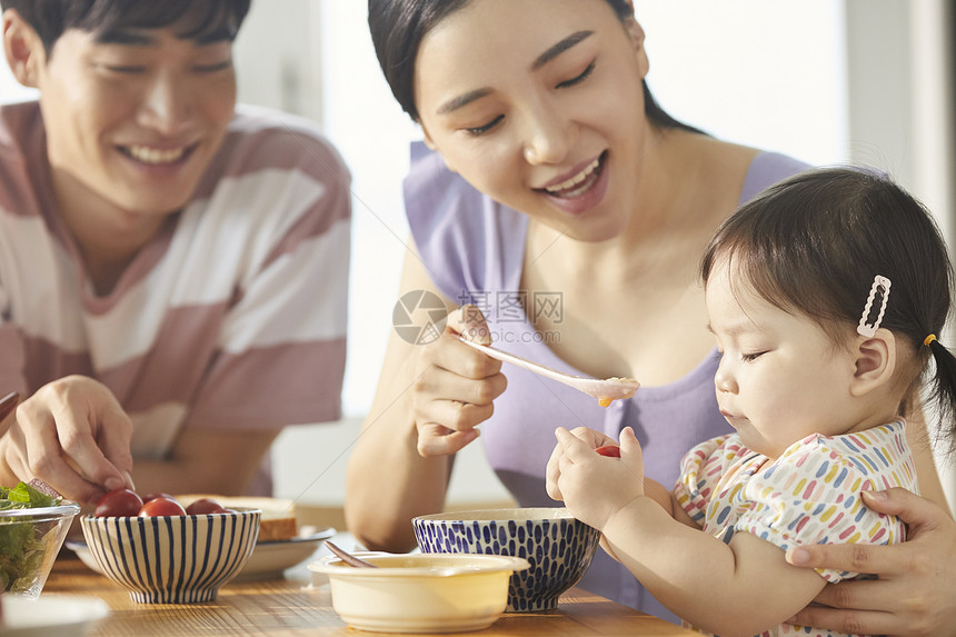 年轻一家人照顾孩子用餐图片