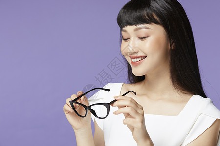 拿着黑框眼镜微笑的年轻女子背景图片