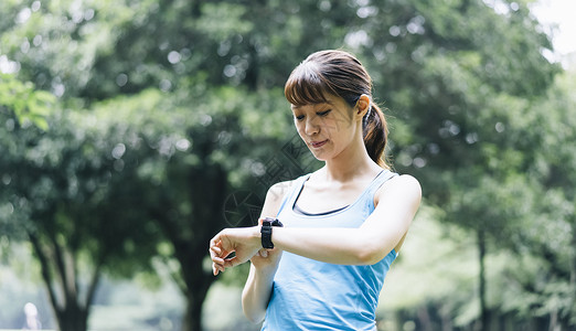 低头看着手表的运动女性背景图片