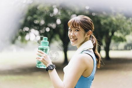 户外拿着水瓶的青年女子笑容高清图片素材