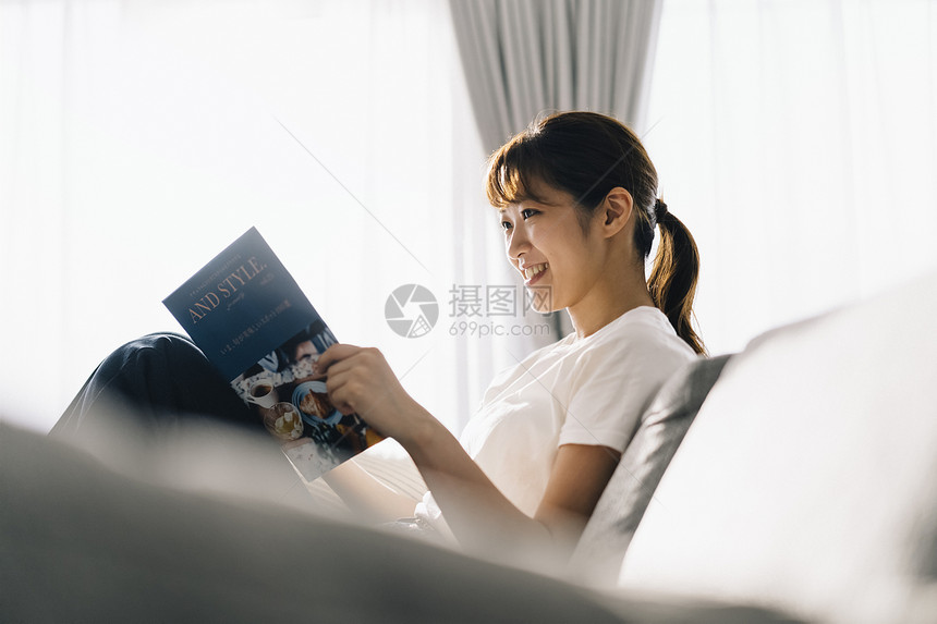 坐在沙发上看书的女士图片