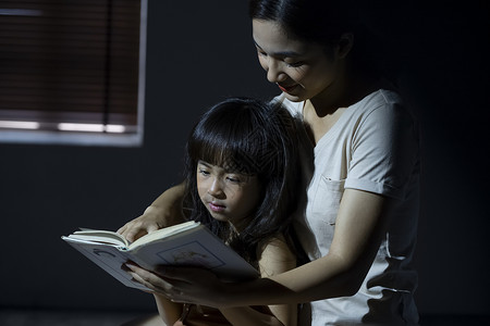 晚上妈妈给女儿阅读书籍小学生高清图片素材