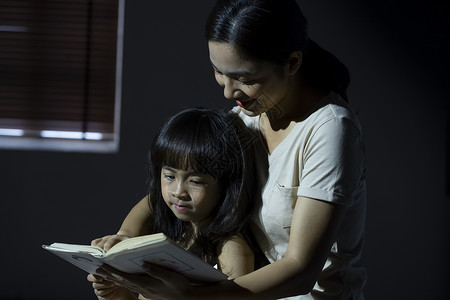 晚上妈妈给女儿阅读书籍母女高清图片素材