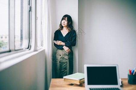 窗边站立着年轻女人图片