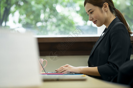 使用笔记本电脑打字工作的女青年笑容高清图片素材