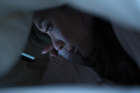 少女感的光线生活方式智能手机上床睡觉背景