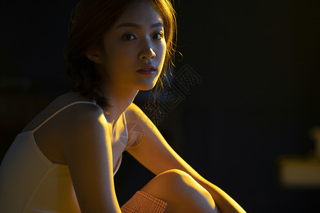 昏黄暖色灯光下的年轻女人背景图片