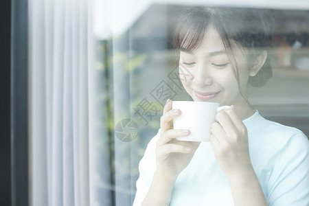 站在窗前喝茶的女孩图片