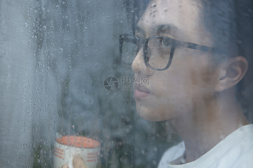 下雨天看向窗外的青年男子图片