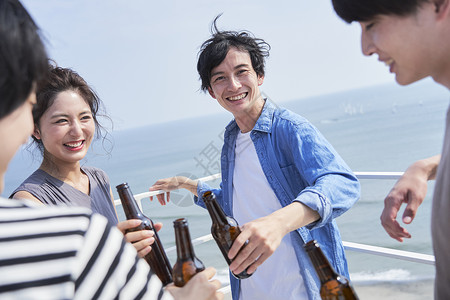 在海边阳台上聚会喝酒的青年男女啤酒高清图片素材