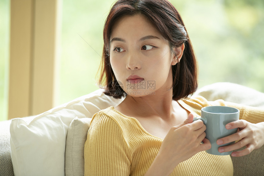 女人靠在沙发里喝咖啡图片