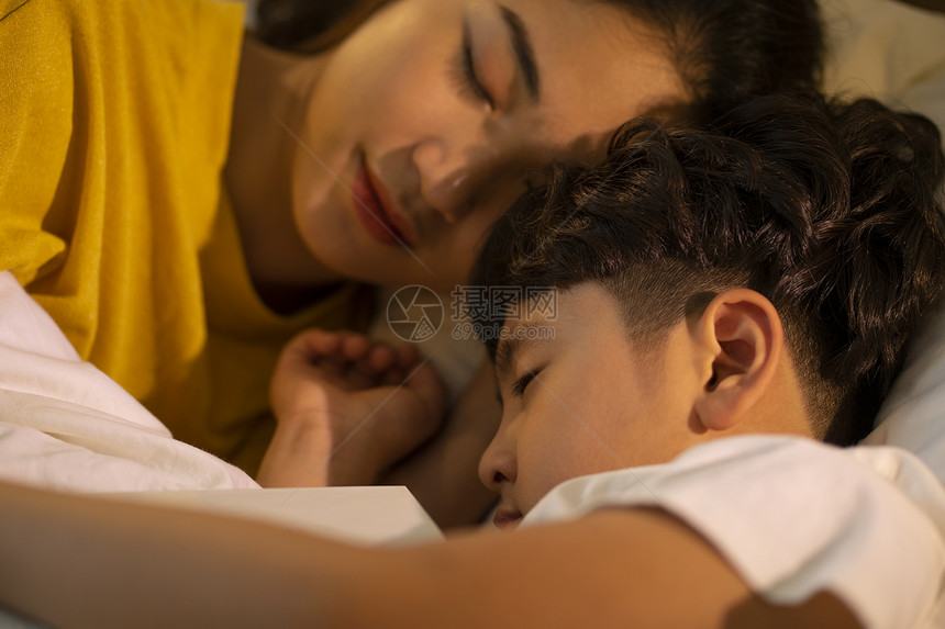母亲陪伴着小男孩睡觉图片