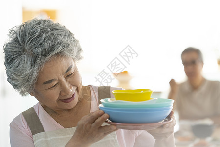 端着盘子微笑的老年女性图片